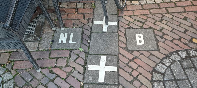 White crosses mark the international border of Baarle. On the left, we see the Netherlands, and on the right, it’s Belgium. 