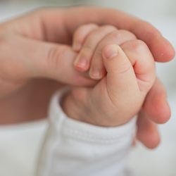 hand of a newborn baby gripping onto an adult's thumb