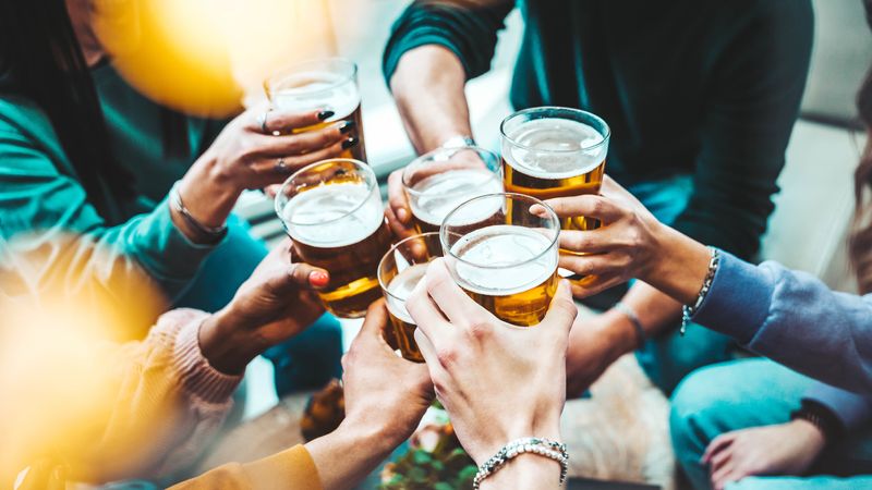 close up aerial view of group of people clinking beer glasses together