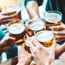close up aerial view of group of people clinking beer glasses together