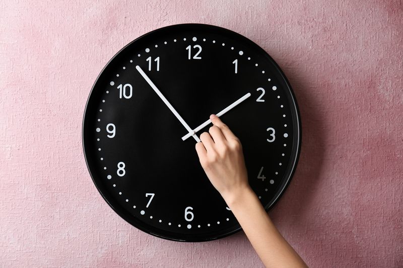 A woman's hand changing an analog clock