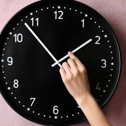 A woman's hand changing an analog clock