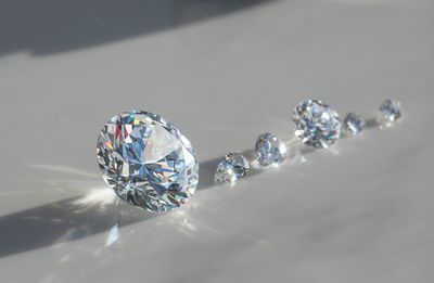 diagonal row of cut diamonds of different sizes, with a massive one first, on a pale background