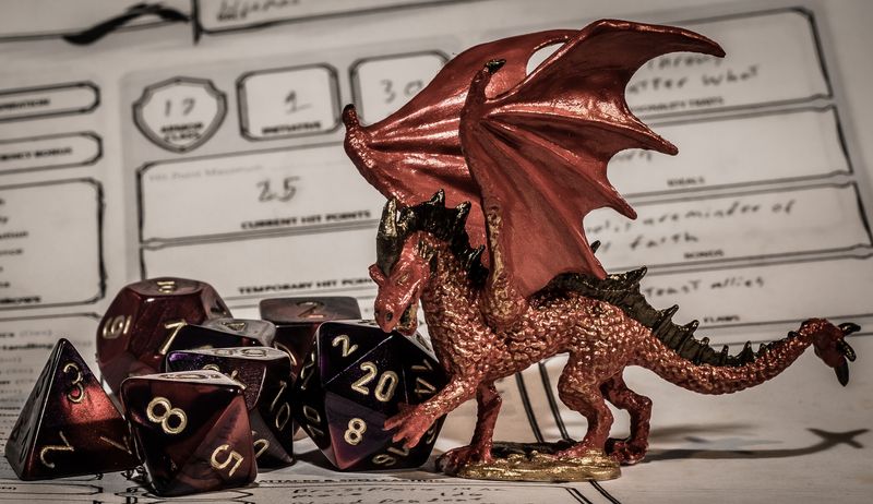 red gaming dice next to a miniature red drag