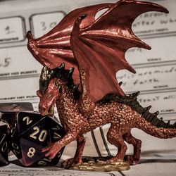 red gaming dice next to a miniature red drag
