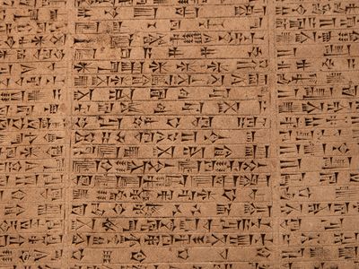 A close up photo showing cuneiform text on a tablet. The words are made up of different lines cut into the surface as various angles. The lines are often short and taper towards one end. 