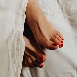 A woman's bare feet with red painted toenails in bed