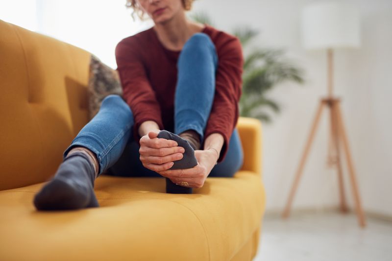 Woman sat on a couch rubbing her foot