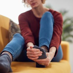 Woman sat on a couch rubbing her foot