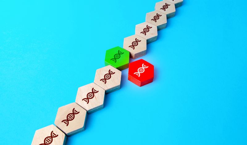 diagonal line of hexagonal wooden tiles on a bright blue background; each tile contains an image of a helix to represent DNA. In the middle of the line, a red tile is being replaced with a green one.