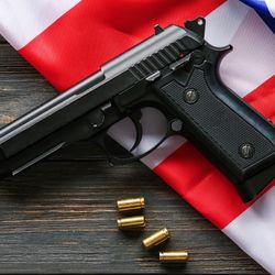 Pistol, bullets and USA flag on wooden background