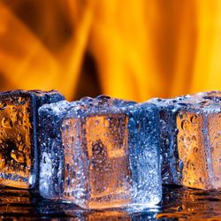 three icecubes melting with a flames behind them