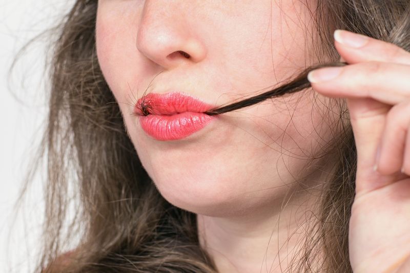 Woman with strands of hair in her mouth