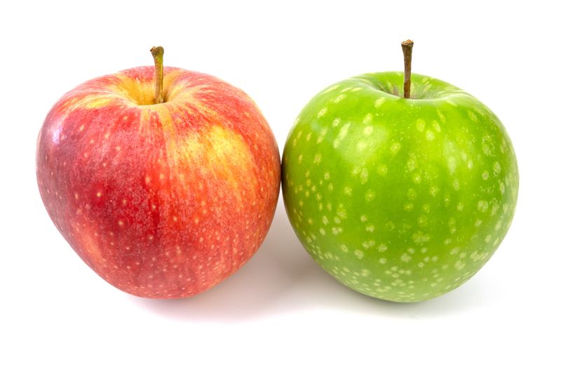 a red and a green apple next to each other on a white background