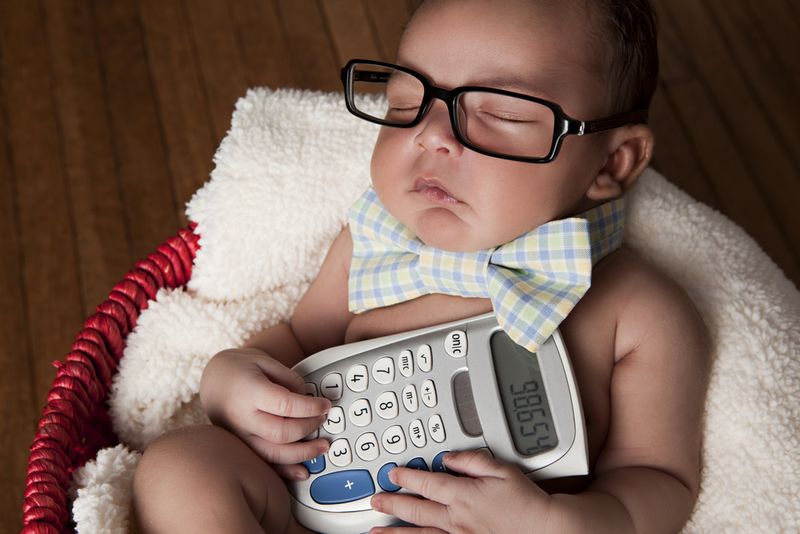 Baby asleep wearing square glasses and holding a calculator 