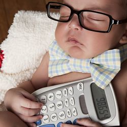 Baby asleep wearing square glasses and holding a calculator 