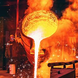 Molten Iron in a factory with a man working hard to keep it running straight.