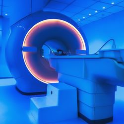 MRI machine; the image is toned blue with the magnetic coil glowing orange