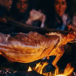 Neanderthals sat around a fire with an animal, maybe a deer, on a spit roast 