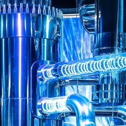 A series of tubes with light spiralling inside connect to a large chrome cylinder.