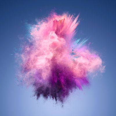 A photo shows an explosion of pink and violet powder forming a spiky cloud. The cloud is set against a blue background.