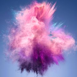 A photo shows an explosion of pink and violet powder forming a spiky cloud. The cloud is set against a blue background.