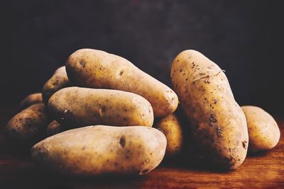 pile of potatoes on a wooden surface with a dark background