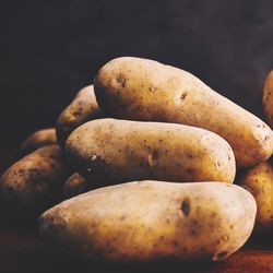 pile of potatoes on a wooden surface with a dark background