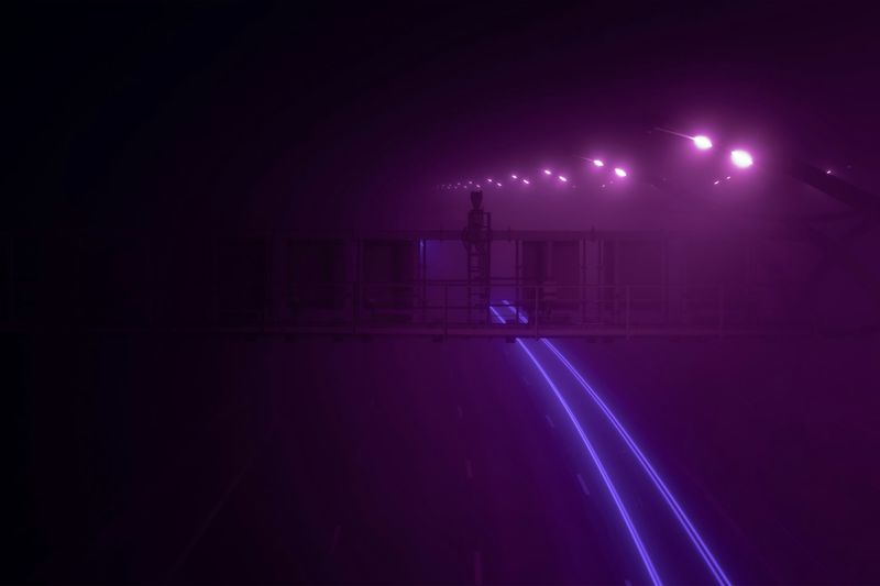 Purple lights on a road at night in the dark.