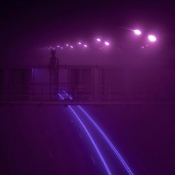 Purple lights on a road at night in the dark.