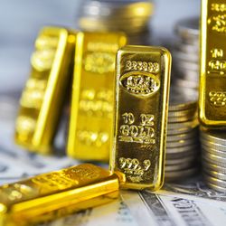 small gold ingots placed on some coins and dollars