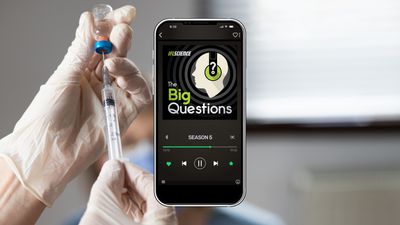 A smartphone showing season 5 of The Big Questions, on background of gloved hands inserting a needle into a vaccine vial
