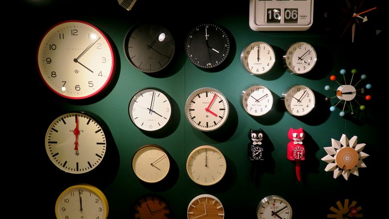A group of clocks on a green wall.