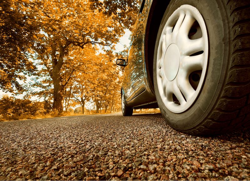 Car tire that is black on standing on the road.