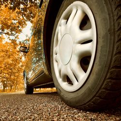 Car tire that is black on standing on the road.