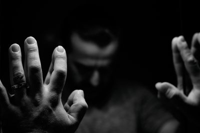 Man in despair with raised hands and bowed hand, monochromatic image in a low light room looking in front of mirror