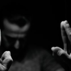 Man in despair with raised hands and bowed hand, monochromatic image in a low light room looking in front of mirror