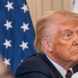 Donald Trump wearing a lot of foundation stares vacantly off camera as hand used phones to photograph him.