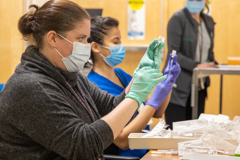 Employees wearing masks drawing up vaccine doses as a walk-in clinic for veterans in Milwaukee in 2021 