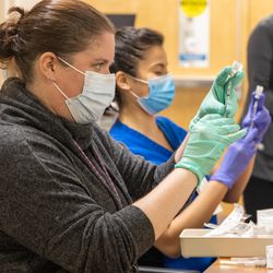 Employees wearing masks drawing up vaccine doses as a walk-in clinic for veterans in Milwaukee in 2021 