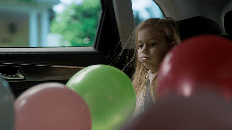 Balloons and a child inside a car.