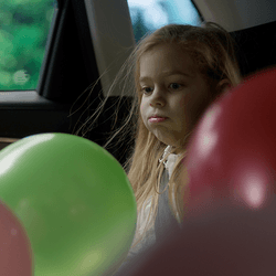 Balloons and a child inside a car.