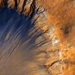 a crater with slopey channels and dark lines across the rocky landscape of mars.
