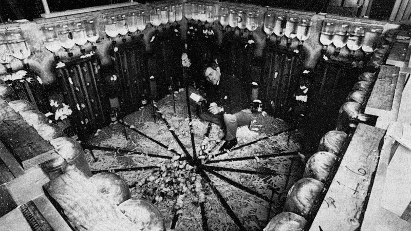 John Calhoun inside a large mouse enclosure with water bottles surrounding it.