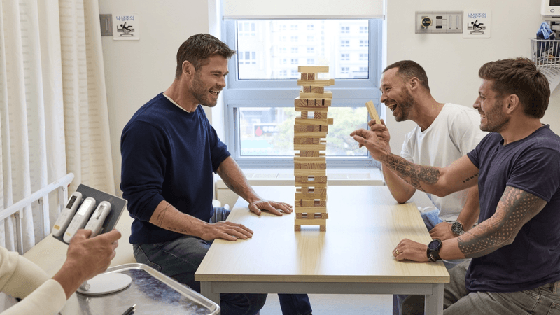 chris hemsworth playing jenga with pads stuck to his stomach that deliver electric shocks