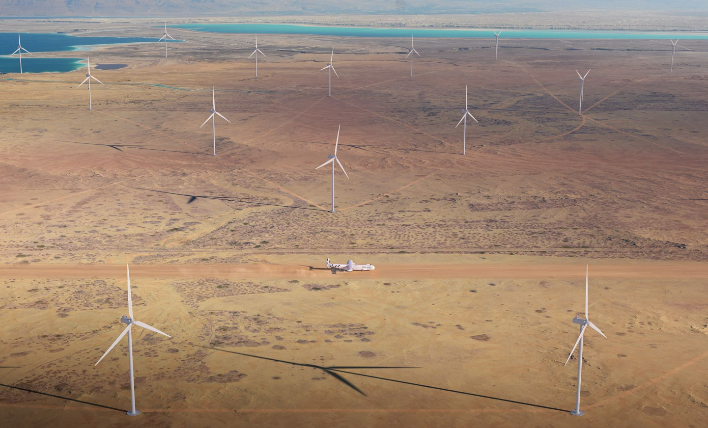 windrunner giant aircraft landing in a desert surrounded by wind turbines